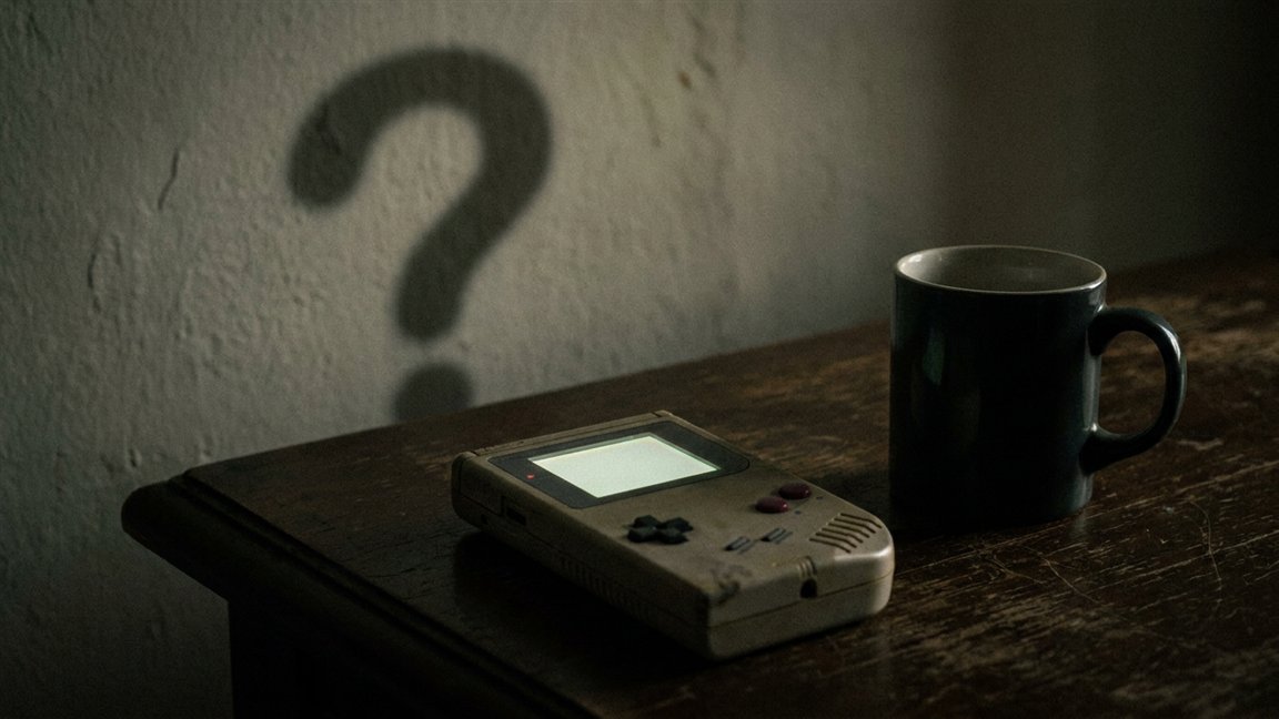 Consola portátil sobre una mesa con una sombra en forma de interrogación